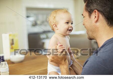 Father holding baby in kitchen View Large Photo Image Stock Image - Father holding baby in kitchen. Fotosearch