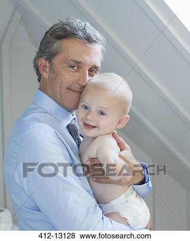 Stock Photo - Father holding baby indoors. Fotosearch