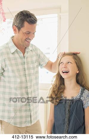 Stock Photography - Father measuring daughter's height on wall. Fotosearch