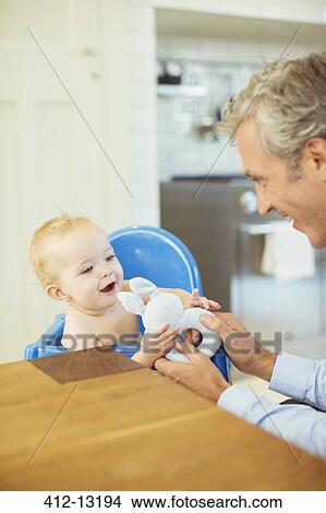 Father playing with baby in high chair View Large Photo Image Picture - Father playing with baby in high chair. Fotosearch