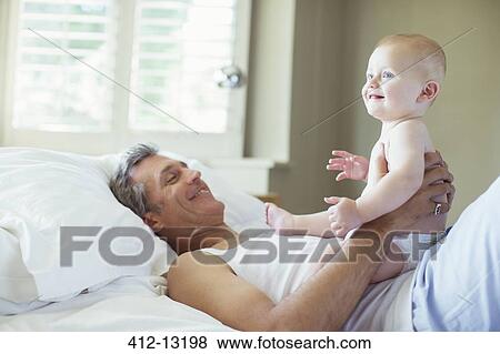 Father playing with baby on bed View Large Photo Image Stock Photo - Father playing with baby on bed. Fotosearch