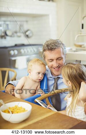 Stock Image - Father talking to children at breakfast. Fotosearch