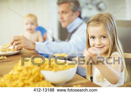 Girl eating overflowing bowl of cereal View Large Photo Image Stock Photo - Girl eating overflowing bowl of cereal. Fotosearch