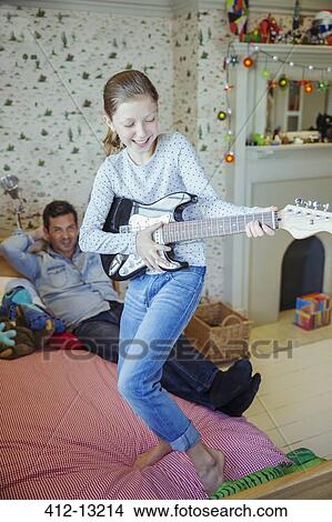 Girl playing guitar for father in bedroom View Large Photo Image Picture - Girl playing guitar for father in bedroom. Fotosearch