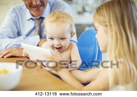 Girl showing baby digital tablet at table View Large Photo Image Stock Photograph - Girl showing baby digital tablet at table . Fotosearch