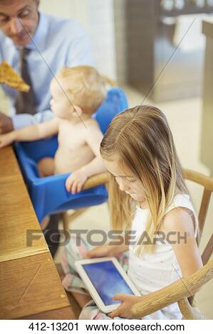 Stock Image - Girl using digital tablet at table. Fotosearch