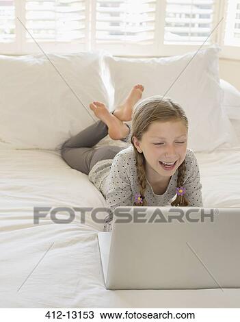 Girl using laptop on bed View Large Photo Image Stock Image - Girl using laptop on bed. Fotosearch