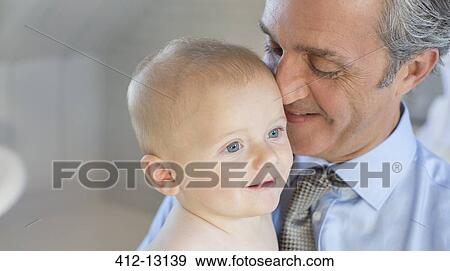 Smiling father holding baby View Large Photo Image Stock Photo - Smiling father holding baby. Fotosearch