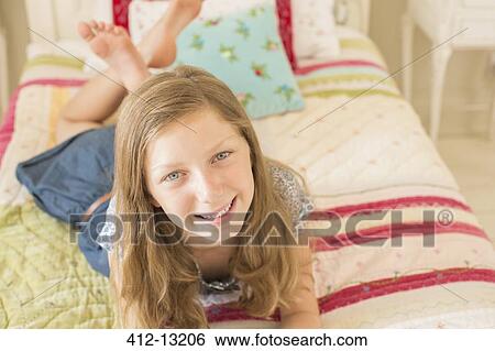 Stock Photograph - Smiling girl laying on bed. Fotosearch