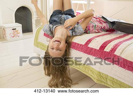 Stock Image - Smiling girl playing on bed. Fotosearch