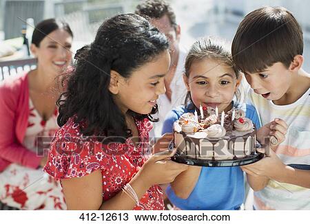 Stock Image - Children holding birthday cake outdoors. Fotosearch