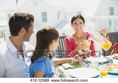 Family eating breakfast on sunny patio View Large Photo Image Stock Photo - Family eating breakfast on sunny patio. Fotosearch