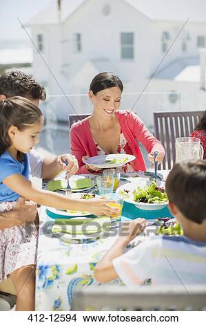 Family eating lunch at table on sunny patio View Large Photo Image Picture - Family eating lunch at table on sunny patio. Fotosearch
