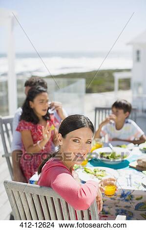 Family eating lunch at table on sunny patio overlooking ocean View Large Photo Image Picture - Family eating lunch at table on sunny patio overlooking ocean. Fotosearch