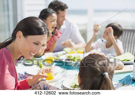 Family eating lunch at table on sunny patio View Large Photo Image Stock Image - Family eating lunch at table on sunny patio. Fotosearch