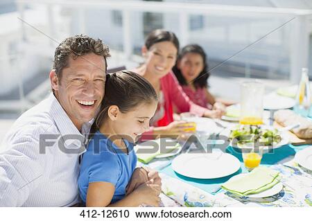 Family eating lunch at table on sunny patio View Large Photo Image Stock Image - Family eating lunch at table on sunny patio. Fotosearch