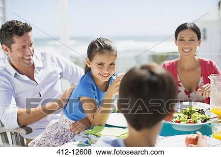 Family eating lunch at table on sunny patio View Large Photo Image Stock Photo - Family eating lunch at table on sunny patio. Fotosearch