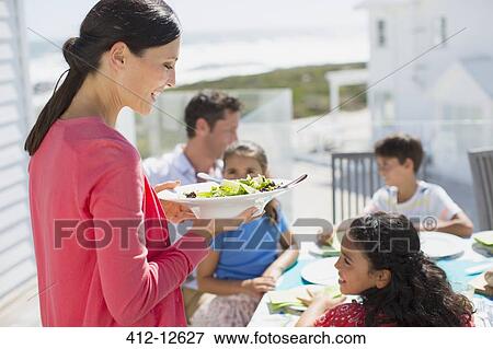 Family eating lunch at table on sunny patio View Large Photo Image Stock Photo - Family eating lunch at table on sunny patio. Fotosearch