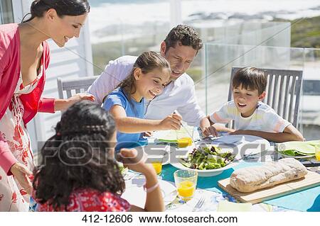 Family eating lunch at table on sunny patio View Large Photo Image Stock Photograph - Family eating lunch at table on sunny patio. Fotosearch