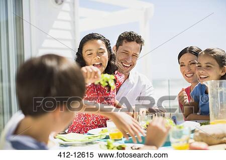 Family eating lunch at table on sunny patio View Large Photo Image Stock Photography - Family eating lunch at table on sunny patio. Fotosearch
