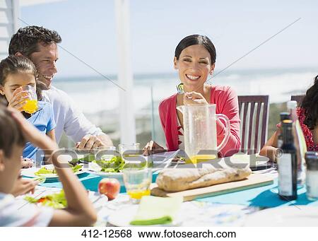 Family eating on patio with ocean in background View Large Photo Image Stock Photo - Family eating on patio with ocean in background. Fotosearch