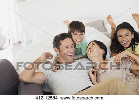 Family laughing and relaxing on sofa View Large Photo Image Picture - Family laughing and relaxing on sofa. Fotosearch