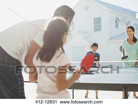 Stock Image - Family playing table tennis outside house. Fotosearch