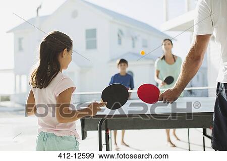 Stock Photo - Family playing table tennis together outdoors. Fotosearch