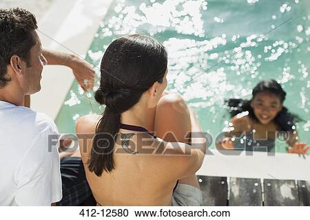 Family relaxing at swimming pool View Large Photo Image Stock Image - Family relaxing at swimming pool. Fotosearch