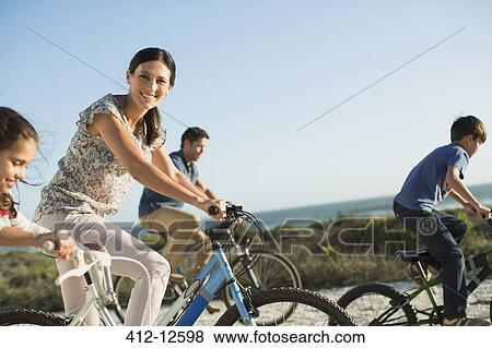 Stock Photo - Family riding bicycles on beach. Fotosearch