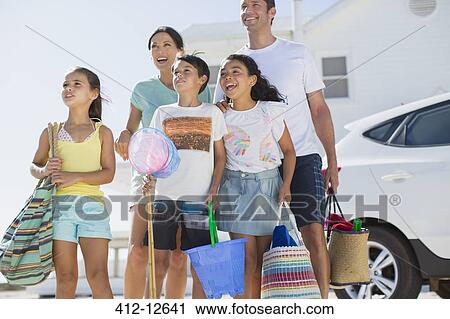 Stock Image - Family standing with beach gear in sunny driveway. Fotosearch