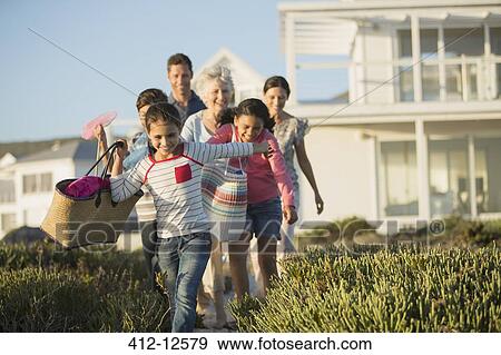 Stock Photo - Family walking on beach path outside house. Fotosearch