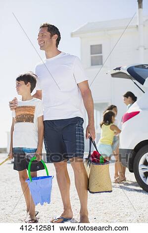 Father and son holding beach gear by car View Large Photo Image Stock Image - Father and son holding beach gear by car. Fotosearch
