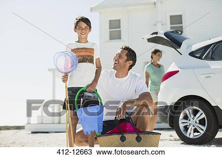 Father and son holding beach gear outside car in sunny driveway View Large Photo Image Stock Image - Father and son holding beach gear outside car in sunny driveway. Fotosearch