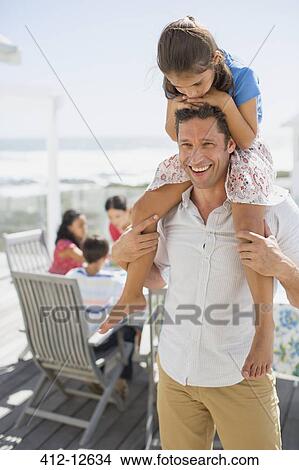 Father carrying daughter on shoulders on sunny patio View Large Photo Image Picture - Father carrying daughter on shoulders on sunny patio. Fotosearch