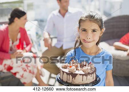 Stock Image - Girl with birthday cake licking lips. Fotosearch