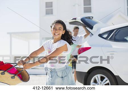 Happy girl swinging beach bag outside car in sunny driveway View Large Photo Image Stock Image - Happy girl swinging beach bag outside car in sunny driveway. Fotosearch