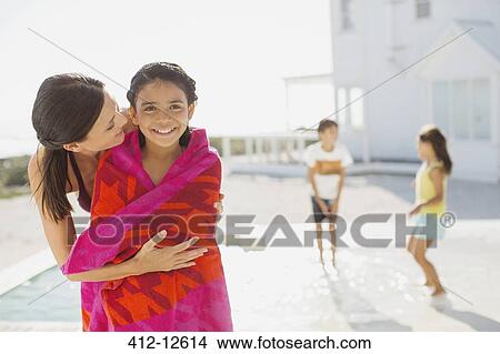 Picture - Mother wrapping daughter in towel at poolside. Fotosearch