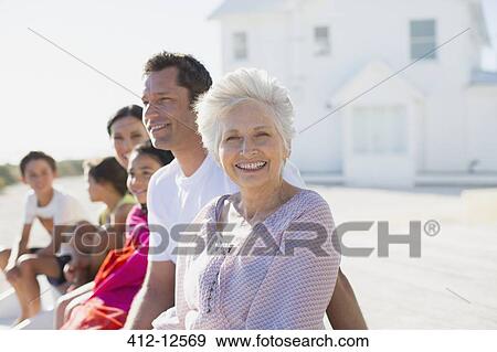 Multi-generation family smiling outside beach house View Large Photo Image Stock Photo - Multi-generation family smiling outside beach house. Fotosearch