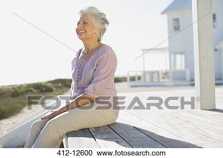 Senior woman sitting on deck outside beach house View Large Photo Image Stock Image - Senior woman sitting on deck outside beach house. Fotosearch