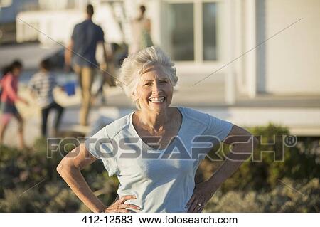 Stock Image - Senior woman smiling with hands on hips outdoors. Fotosearch