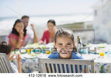 Smiling girl at table on sunny patio View Large Photo Image Stock Photo - Smiling girl at table on sunny patio. Fotosearch
