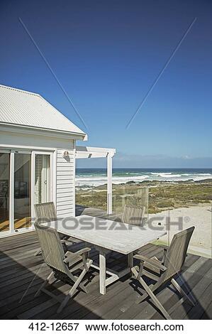 Table and chairs on patio overlooking beach View Large Photo Image Stock Photo - Table and chairs on patio overlooking beach. Fotosearch