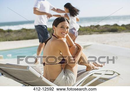 Woman relaxing on lounge chair at poolside View Large Photo Image Stock Image - Woman relaxing on lounge chair at poolside. Fotosearch