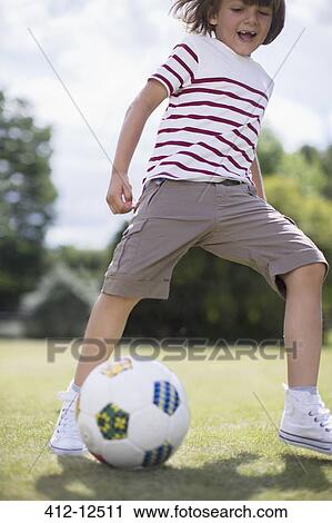 Stock Image - Boy playing soccer outdoors. Fotosearch