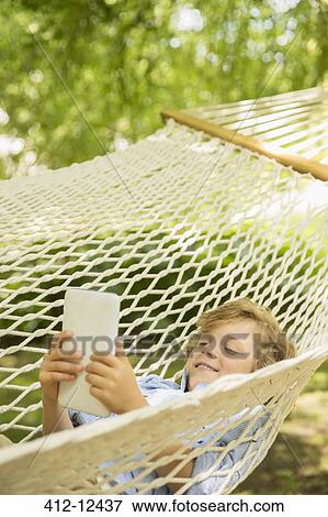 Boy using digital tablet in hammock View Large Photo Image Stock Photo - Boy using digital tablet in hammock. Fotosearch