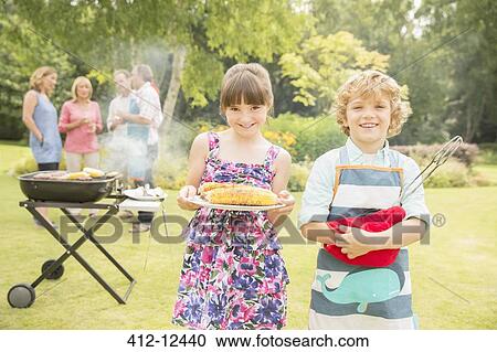 Brother and sister holding grilled corn near barbecue in backyard View Large Photo Image Stock Image - Brother and sister holding grilled corn near barbecue in backyard. Fotosearch