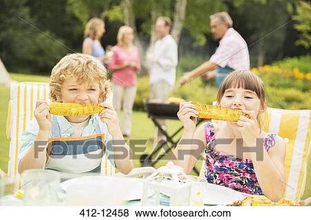Stock Photo - Children eating at table in backyard. Fotosearch