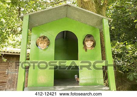 Stock Image - Children peeking through windows of treehouse. Fotosearch