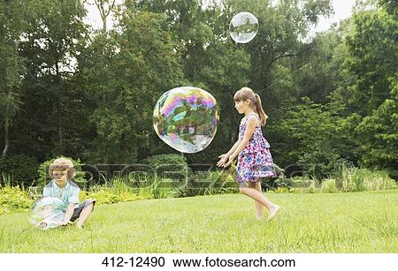 Children playing with bubbles in backyard View Large Photo Image Stock Image - Children playing with bubbles in backyard. Fotosearch